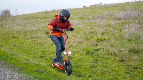 Man riding the Qiewa electric scooter up a grass hill