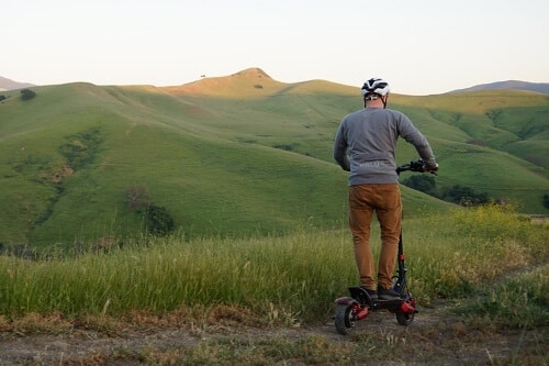 Man riding an electric scooter up a hill