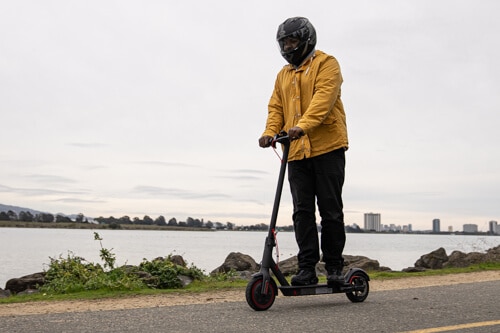 Xiaomi M365 Pro electric scooter - man riding to left of frame, full view