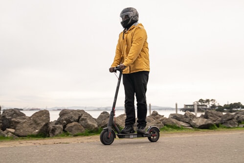 Xiaomi M365 Pro electric scooter - man riding to left of frame, upright, full view