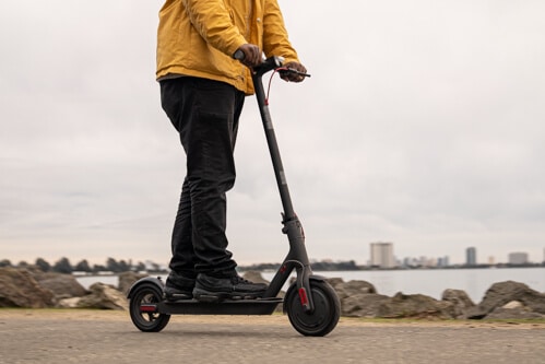 Xiaomi M365 Pro electric scooter - man riding to right of frame, cropped at waist