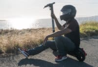 Man crouched next to the Xr Elite electric scooter