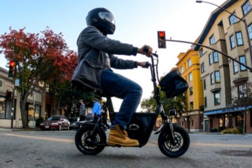 Man cruising in traffic on a seated electric scooter