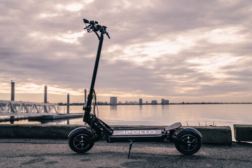 Apollo Ghost electric scooter - full scooter, side view, handlebars on left, cityscape on skyline