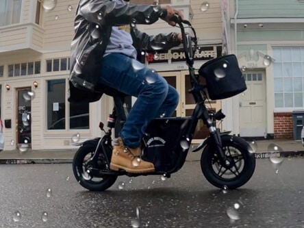 Fiido Q1S seated electric scooter - man riding scoter in rain, cropped, side shot