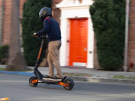 Inokim OXO Electric Scooter - man riding to left of frame, side view, full view