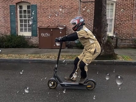 Segway Ninebot Max electric scooter - man riding in rain, braking on scooter, side shot