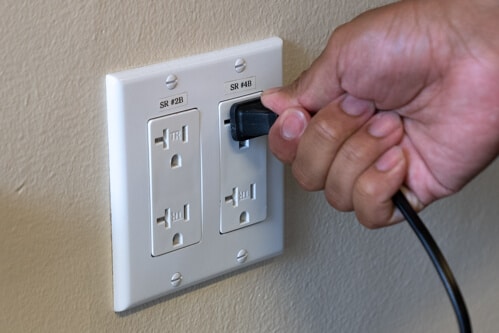Man plugging charger into AC wall outlet