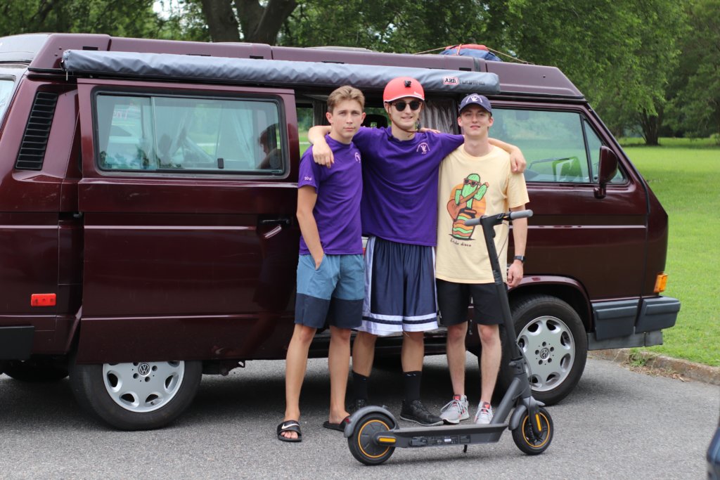 Brandon, Graham, and Christian in front of the VW Vanagon Westfalia with a Segway Ninebot Max scooter in front of them