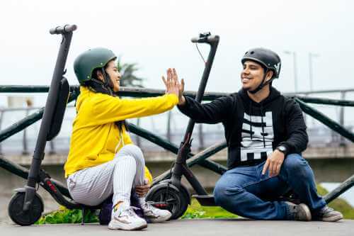 2 people high five while sitting on scooters