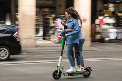 Two girls riding electric scooter without helmets