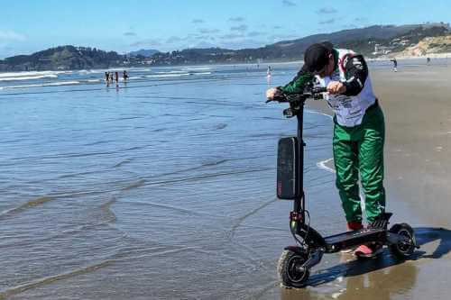 Alex Simon touches scooter to the Pacific Ocean in Newport, Oregon (USA) at end of trip