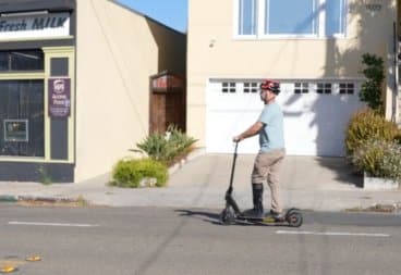 Man in ankle boot riding an electric scooter on the street