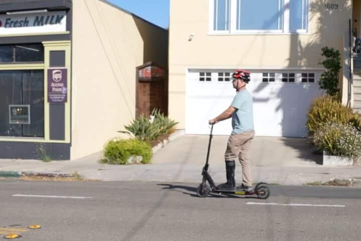 Man in ankle boot riding an electric scooter on the street
