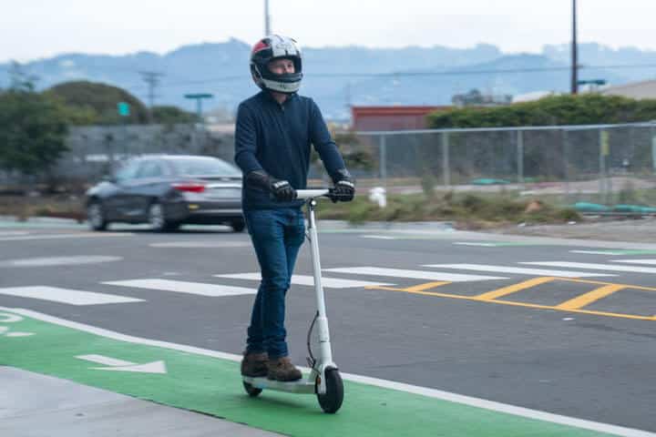 Man riding an Okai Neon e-scooter in the bike lane